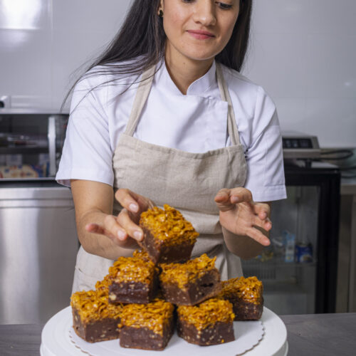 Colombian pastry chef placing brownie pieces on a presentation tray. Colombian pastry chef placing brownie pieces on a presentation tray.